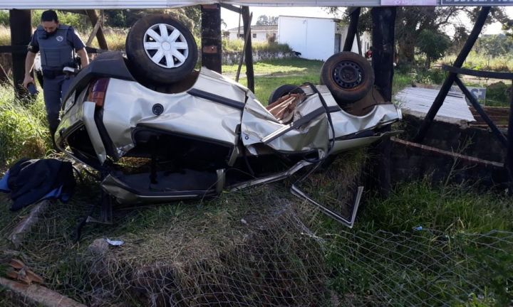 Motorista invade terreno, bate em placa e capota